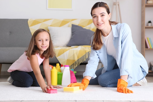 Madre e hija de buen humor están limpiando la casa