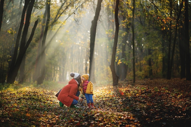 Madre e hija caminando en el parque y disfrutando de la hermosa naturaleza de otoño.