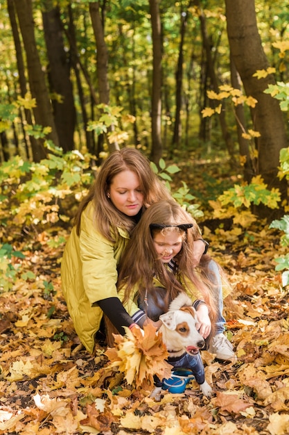 Madre e hija caminando con su perro jack russell terrier en otoño con estilo