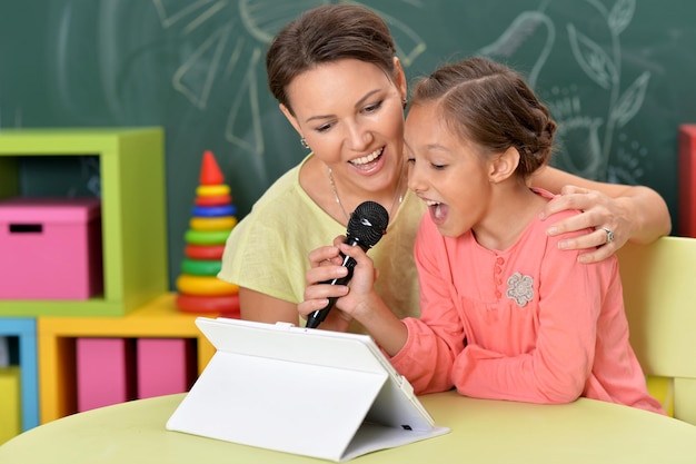 Madre e hija cantando karaoke con micrófono juntas