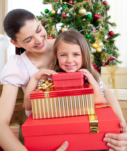 Madre e hija en casa sosteniendo un regalo de Navidad