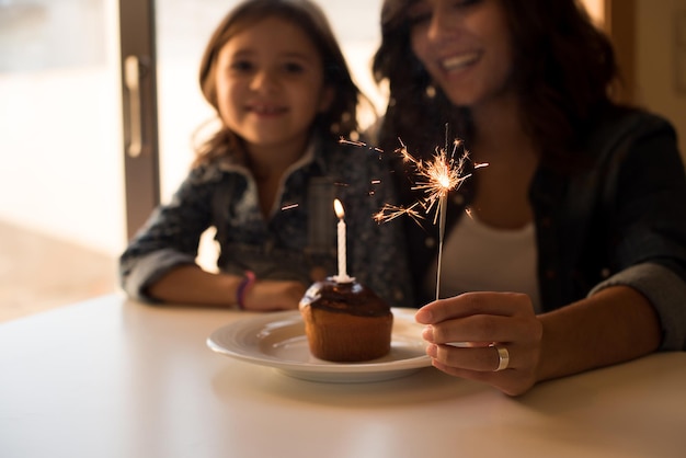 Madre e hija celebrando cumpleaños con cupcake y bengalas