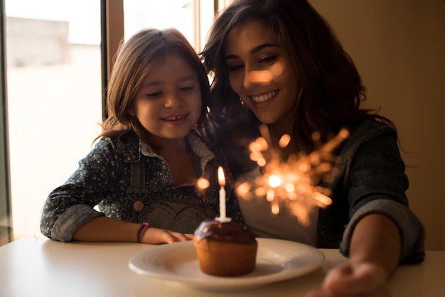 Madre e hija celebrando cumpleaños con cupcake y bengalas