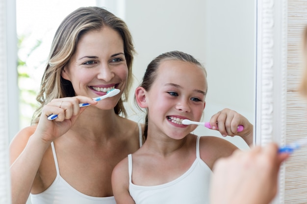 Foto madre e hija se cepillan los dientes en el baño