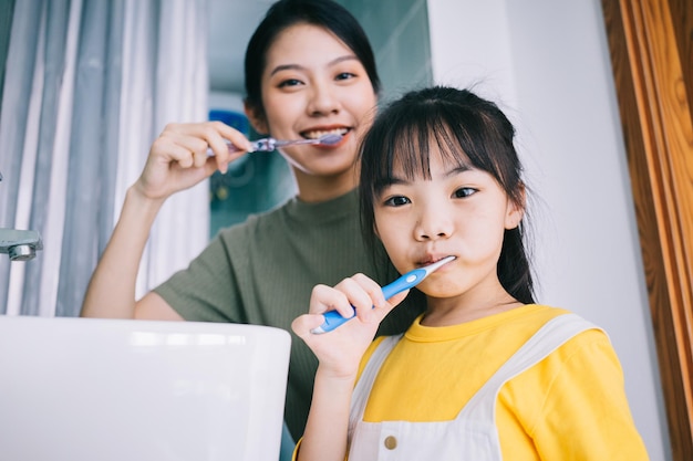 Madre e hija se cepillan los dientes juntas.