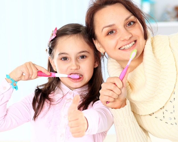 Madre e hija se cepillan los dientes.