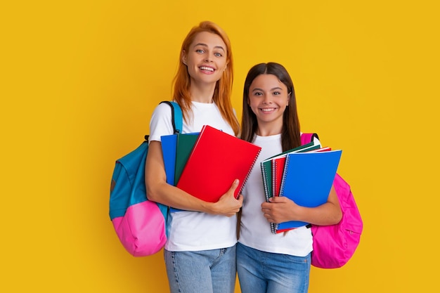 Madre e hija colegialas con mochila escolar y libros listos para aprender Regreso a la escuela Mamá e hijo sobre fondo de estudio amarillo aislado