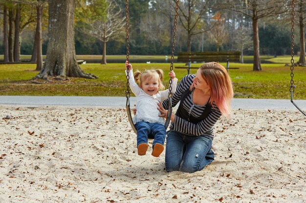 Madre e hija en un columpio en el parque