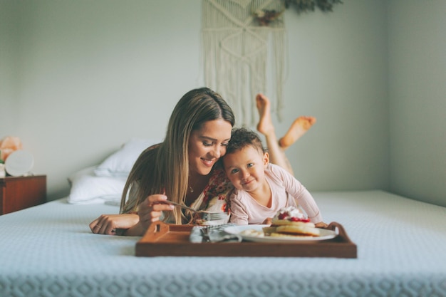 Madre e hija comiendo en la cama en casa