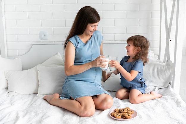 Madre e hija comiendo galletas de chocolate y bebiendo leche