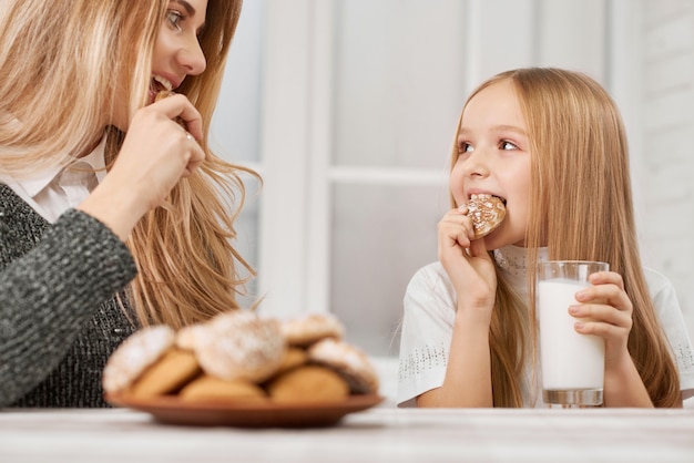 Madre e hija comiendo galletas y sonrisa