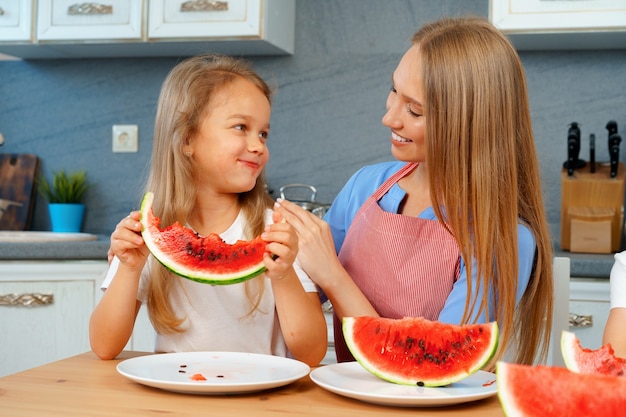 Madre e hija comiendo sandía en casa