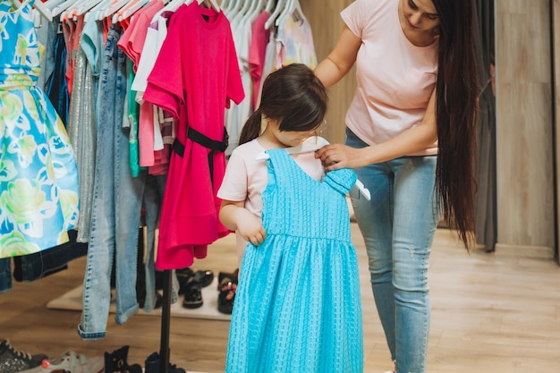 Madre e hija compran ropa madre y niña probándose ropa en la tienda