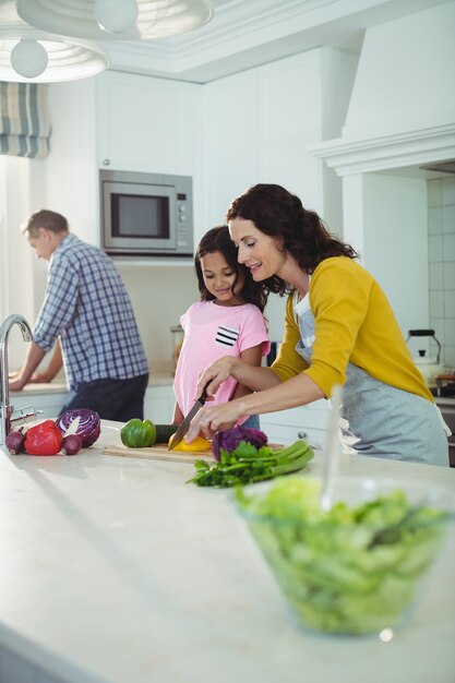 Foto madre e hija cortando verduras en la cocina