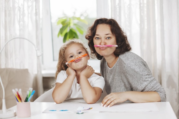 Foto madre e hija dibujan juntas a una chica encantadora y su madre alegre