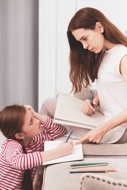 Madre e hija dibujando con lápices de colores en el libro