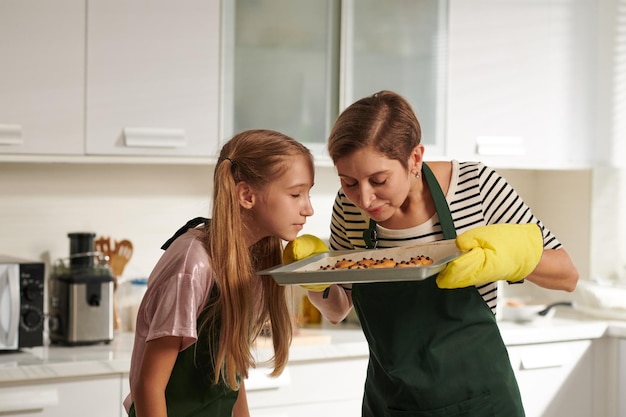 Madre e hija disfrutando del olor a galletas de jengibre recién horneadas