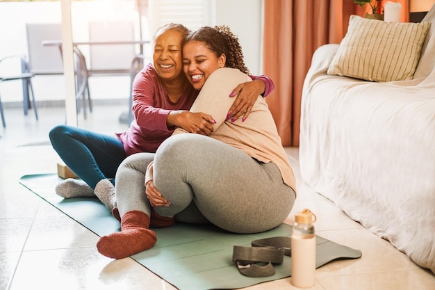 Madre e hija divirtiéndose haciendo ejercicios de fitness en casa Concepto familiar y deportivo en invierno Centrarse en las manos de las mujeres mayores