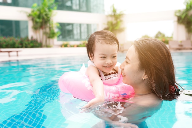 Madre e hija divirtiéndose en la piscina. Vacaciones de verano y concepto de vacaciones.