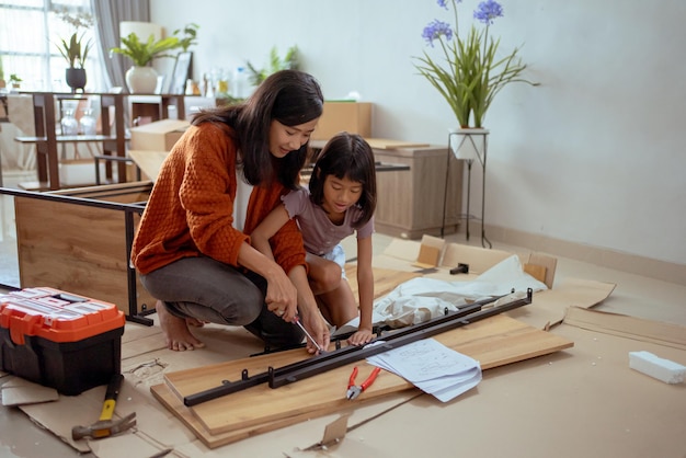 Madre e hija ensamblando muebles nuevos juntos