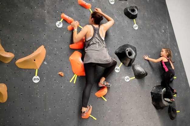 Madre e hija escalando la pared en el gimnasio