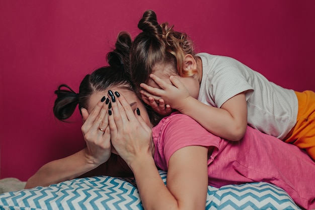 Madre e hija escondida con las manos.