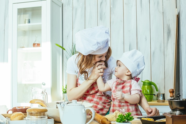 Madre e hija felices y hermosas preparan pasteles y harina en la cocina de casa