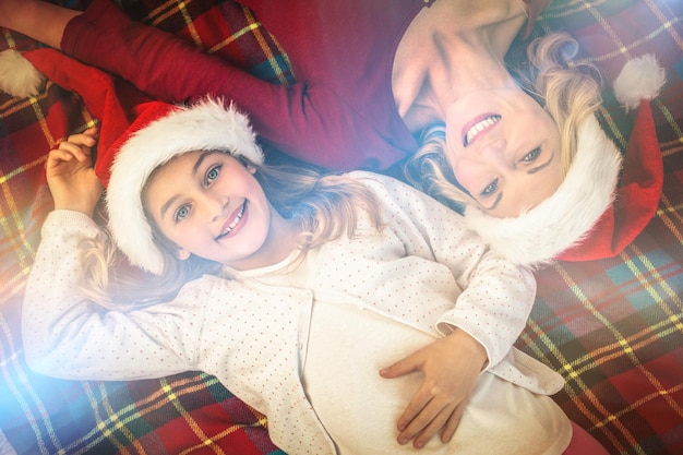 Madre e hija festivas sonriendo a la cámara en una manta en casa en la sala de estar