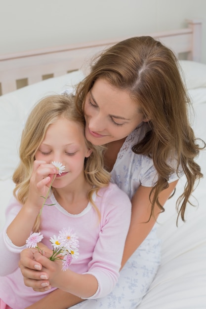 Madre e hija con flores en el dormitorio