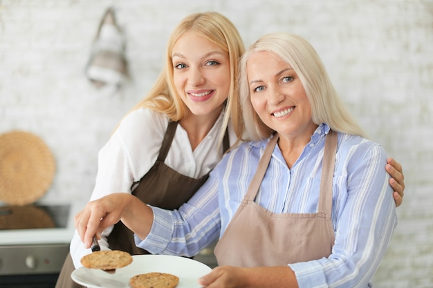 Madre e hija con galletas recién horneadas en la cocina