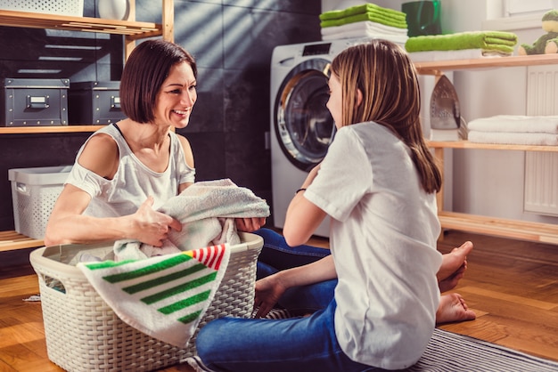 Madre e hija hablando y clasificando la ropa en el piso