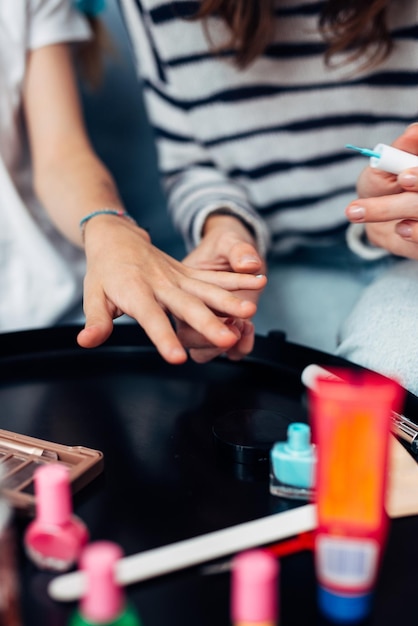 Foto madre e hija haciendo manicura en casa pintando uñas con esmalte de uñas