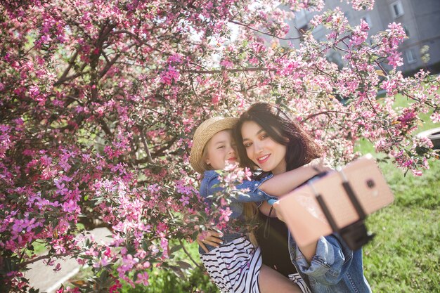 Madre e hija haciendo selfie en el parque. Chicas disparando en el teléfono celular