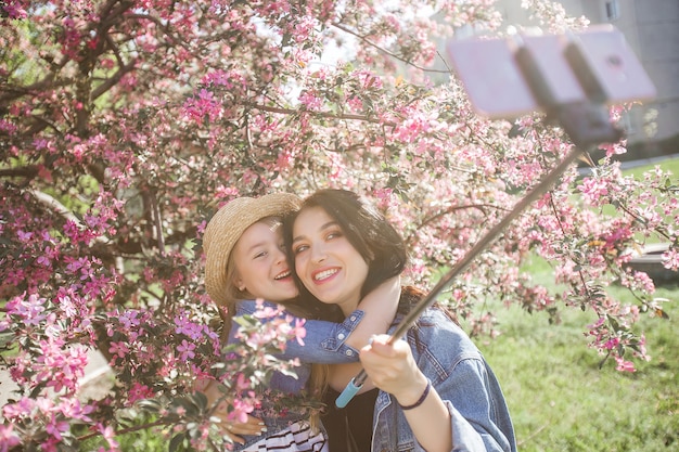 Madre e hija haciendo selfie en el parque. Chicas disparando en el teléfono celular