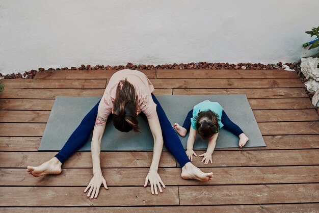 Foto madre e hija haciendo yoga en la casa