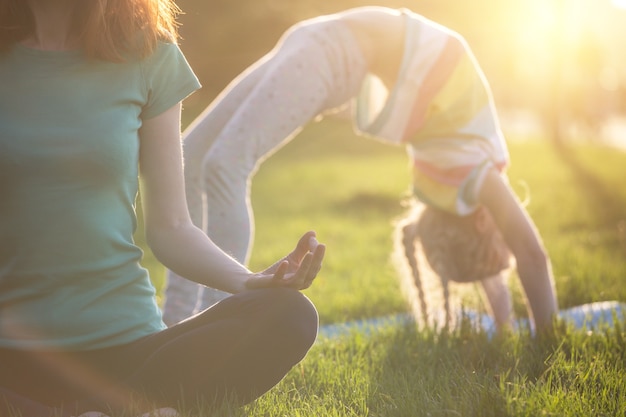 madre e hija haciendo yoga en el parque