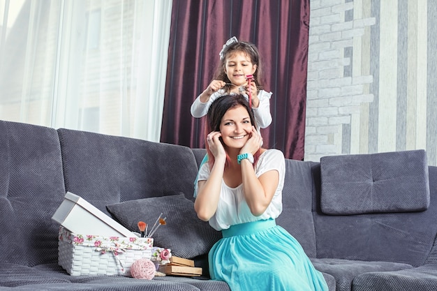 Madre e hija hermosa y feliz en casa en la sala de estar en el sofá