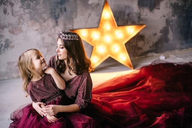 Madre e hija en la imagen de la reina y la princesa se visten con los colores de Marsala con una larga cola en el desván