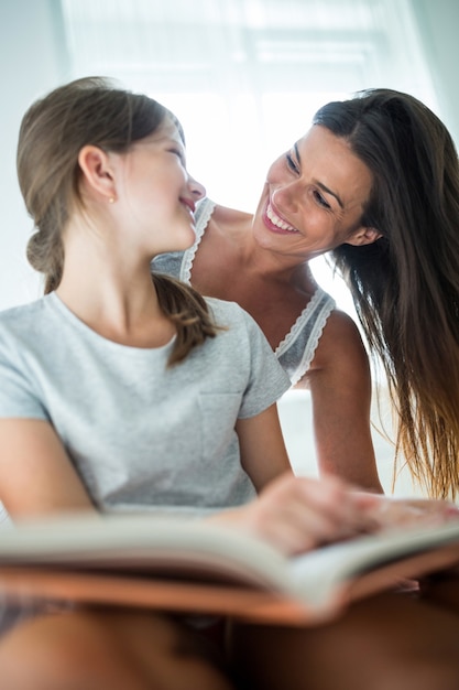 Madre e hija interactuando mientras leía el libro en la cama