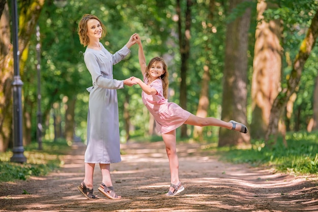 Madre e hija juegan a bailar en el parque. Concepto de familia feliz. Escena de belleza natural con estilo de vida familiar al aire libre. Familia feliz descansando juntos. Felicidad y armonía en la vida familiar.