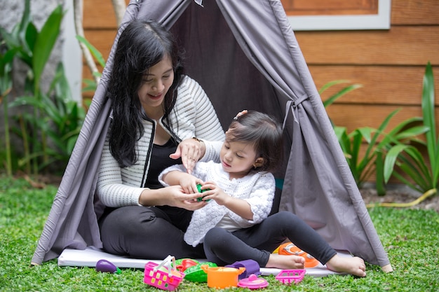 Madre e hija juegan juguetes en el patio trasero