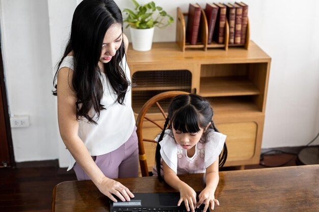 Madre e hija jugando juntos en la computadora portátil en la sala de estar en casa. Concepto de familia amorosa feliz.