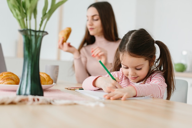 Madre e hija jugando mientras desayunando en la cocina.