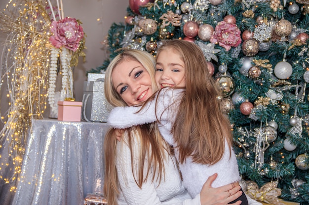 Madre e hija junto al árbol de Navidad. Vacaciones de año nuevo y navidad. Hermosa madre e hija.