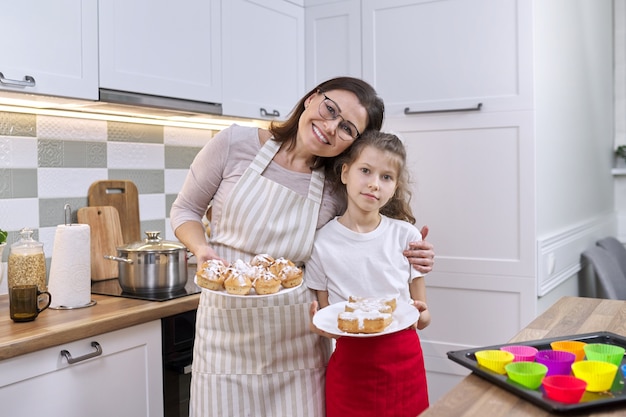 Madre e hija junto en la cocina de casa con muffins recién horneados. Foto para álbum de casa, familia, día de la madre, horneado casero de alimentos saludables