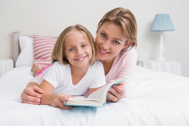 Madre e hija leyendo el libro juntos en la cama