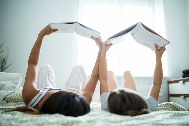 Madre e hija, libro de lectura, en cama