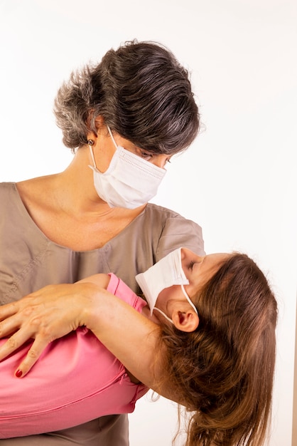 Madre e hija con máscaras protectoras sobre fondo blanco.