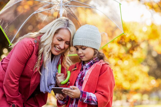 Madre e hija mirando en el celular en el parque