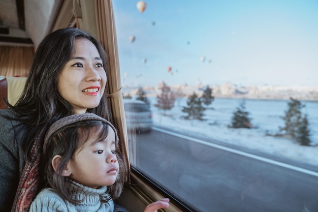 Madre e hija mirando fuera de la ventana de un automóvil a una hermosa vista de capadocia llena de calor